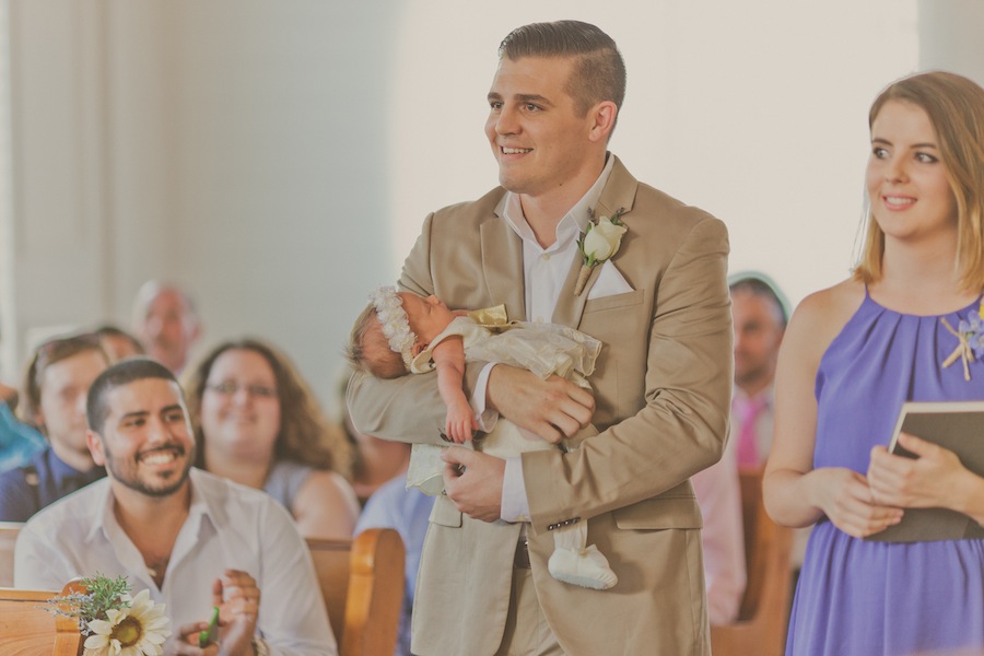 Groom Carrying Flower Girl Down the Aisle on Wedding Day