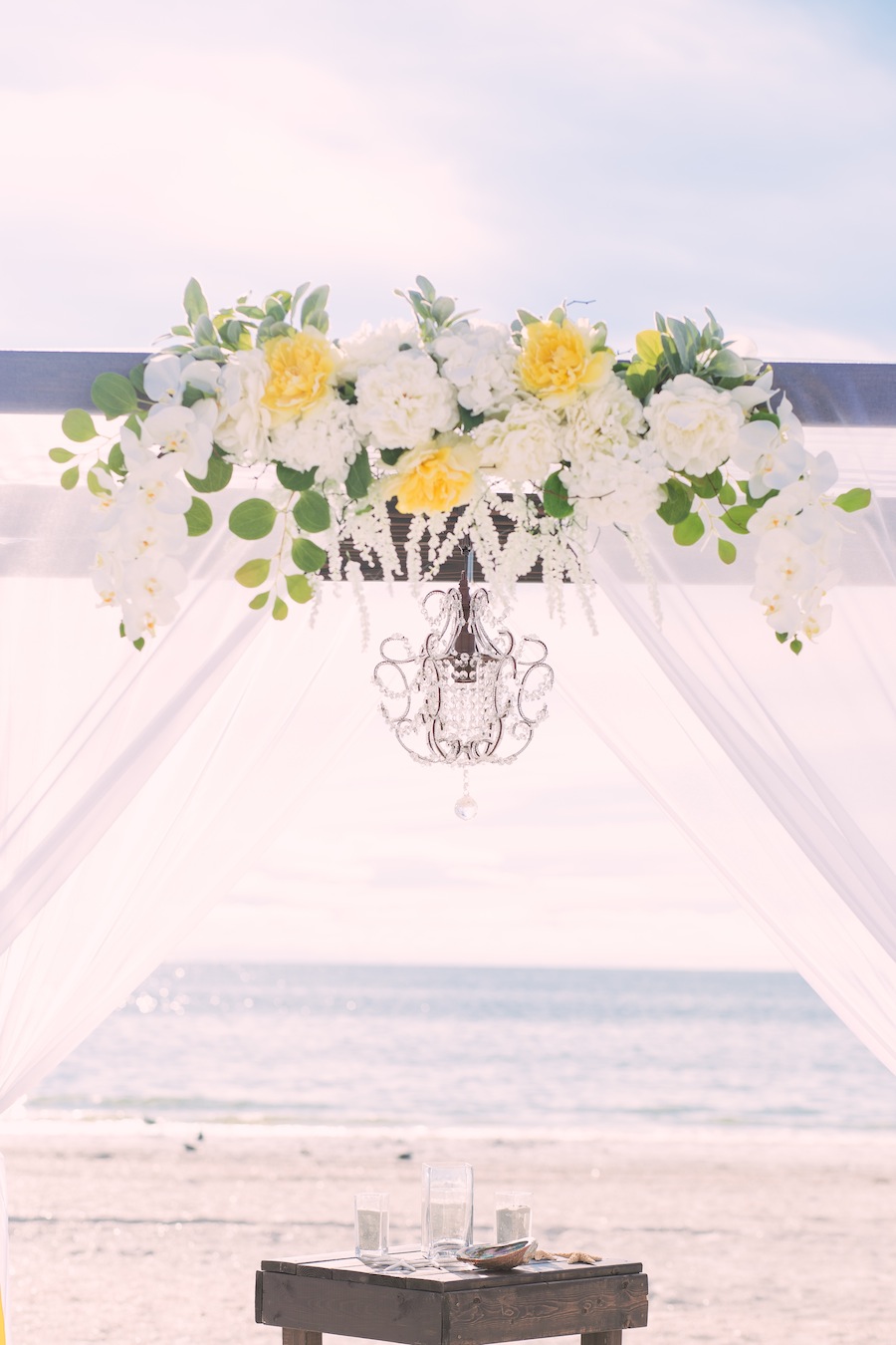 Beach Wedding Ceremony Decor | Wooden Alter with Yellow and White Flowers and Chandelier