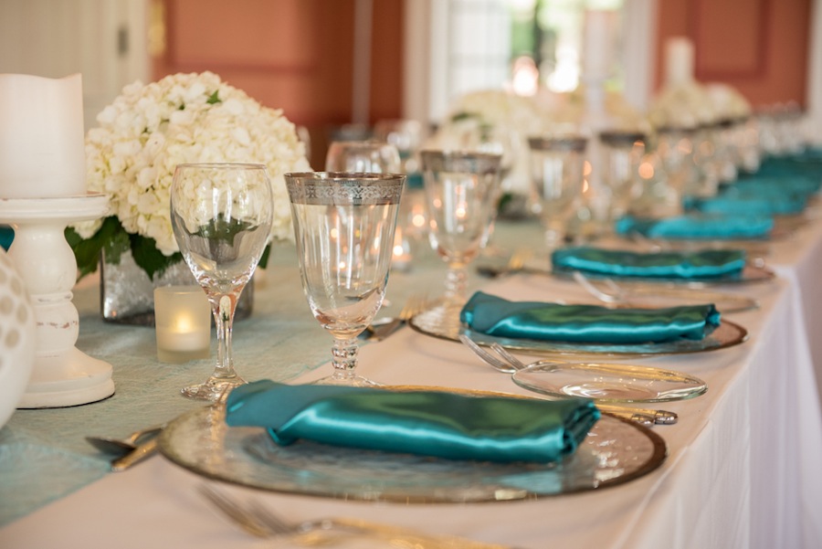 Indoor Sarasota Teal Wedding Reception with Glass Chargers and White Centerpieces