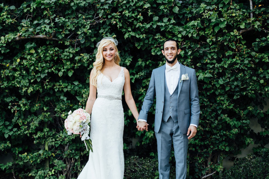 Outdoor, Bride and Groom Wedding Portrait Holding Hands With a Wall of Greenery