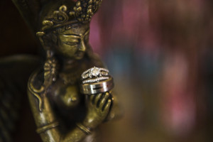 Bride and Groom Wedding Bands and Engagement & Wedding Ring Detail on Buddha Statue