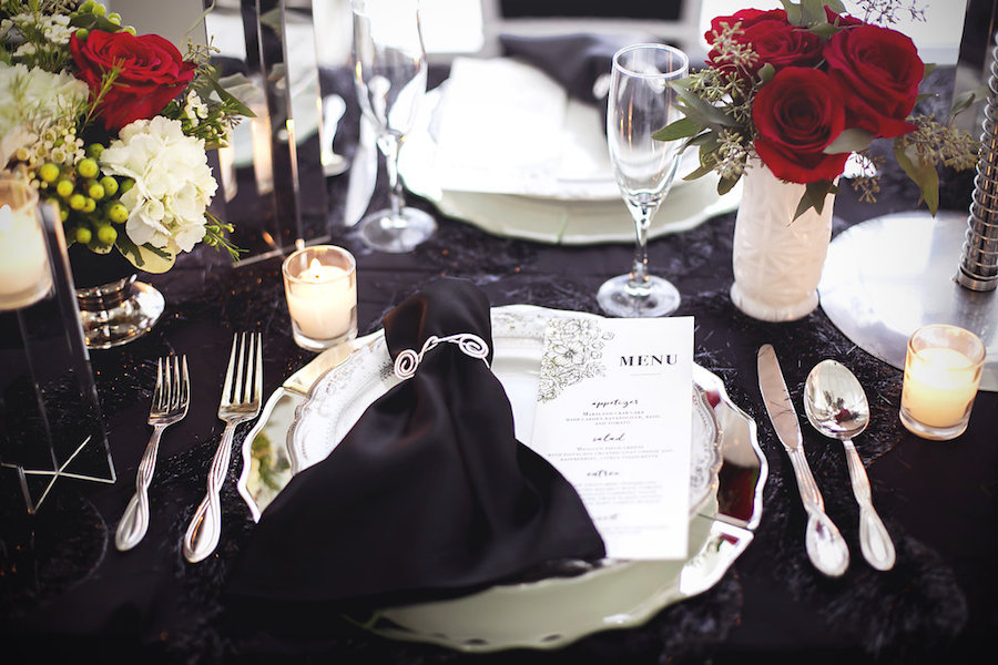 Wedding Reception Table Decor with Silver Chargers and Red Roses | Reception Table Decor of Short, Red Roses and Tea Lights | Modern Black Linen, White Chiavari Chairs, and Red, Ivory and Green Centerpieces | Tampa Wedding Florist Apple Blossoms Floral Design