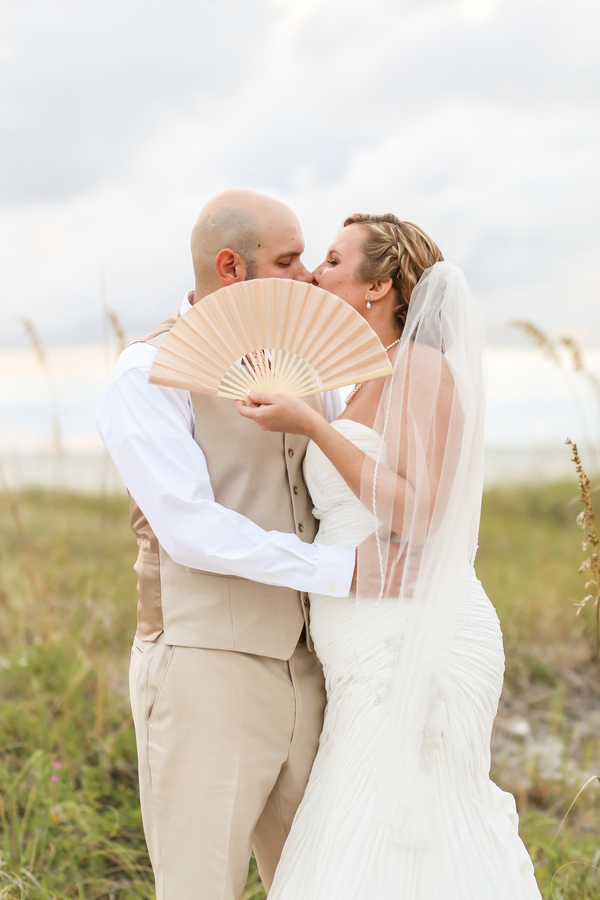St. Pete Beach Bride and Groom Waterfront Wedding Portrait Kissing Behind Fan