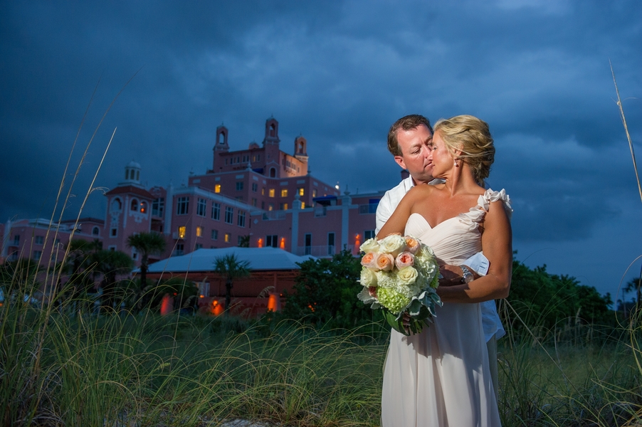 Sunset Bride and Groom Destination Beach Wedding Portraits with Ivory and Coral Bridal Bouquet in front of St. Pete Beach Wedding and Event Venue Loews Don Cesar Resort "The Pink Palace" | St. Petersburg Weddig Photographer Andi Diamond Photography