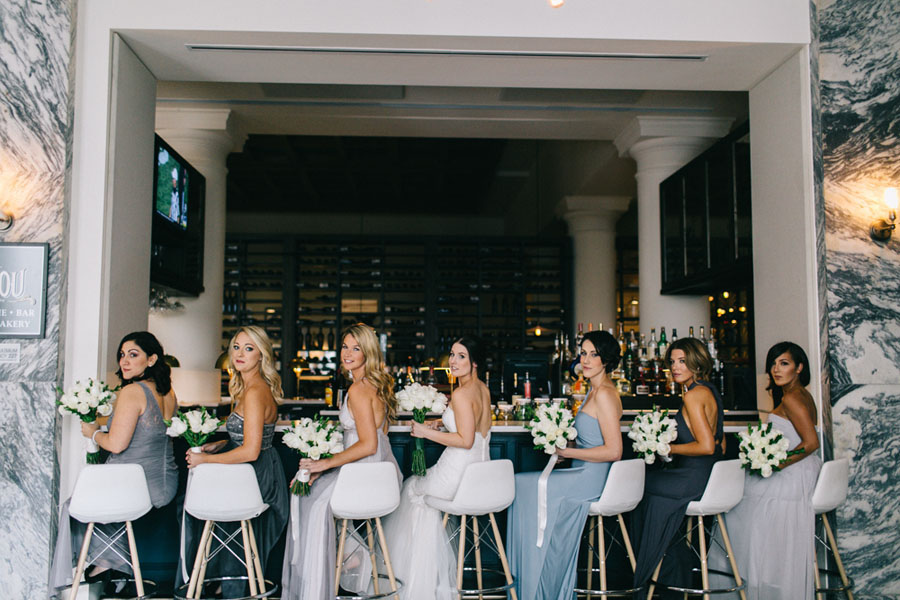 Bride and Grey and Blue Bridesmaids Dresses at Bizou Cafe Bar at Downtown Tampa Wedding Venue Le Meridien Tampa Holding White Bouquets of White Flowers