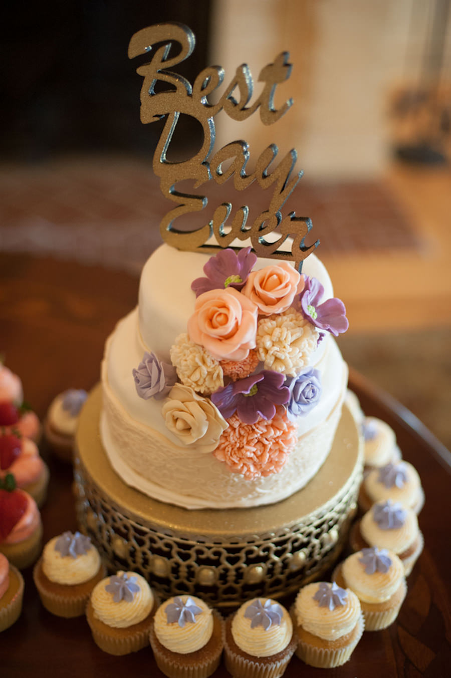 Two Tiered White Wedding Cake with Peach and Purple Edible Flowers and White and Purple Cupcakes