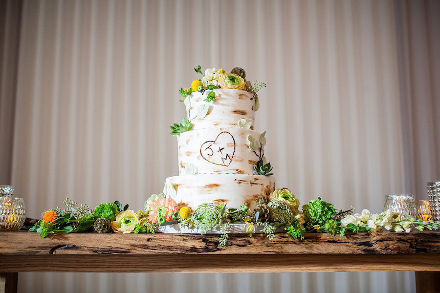 Three Tiered, White, Rustic Wooden Tree Inspired Wedding Cake with Carved Bride and Groom Initials, Accented with Yellow, Green, and White Flowers
