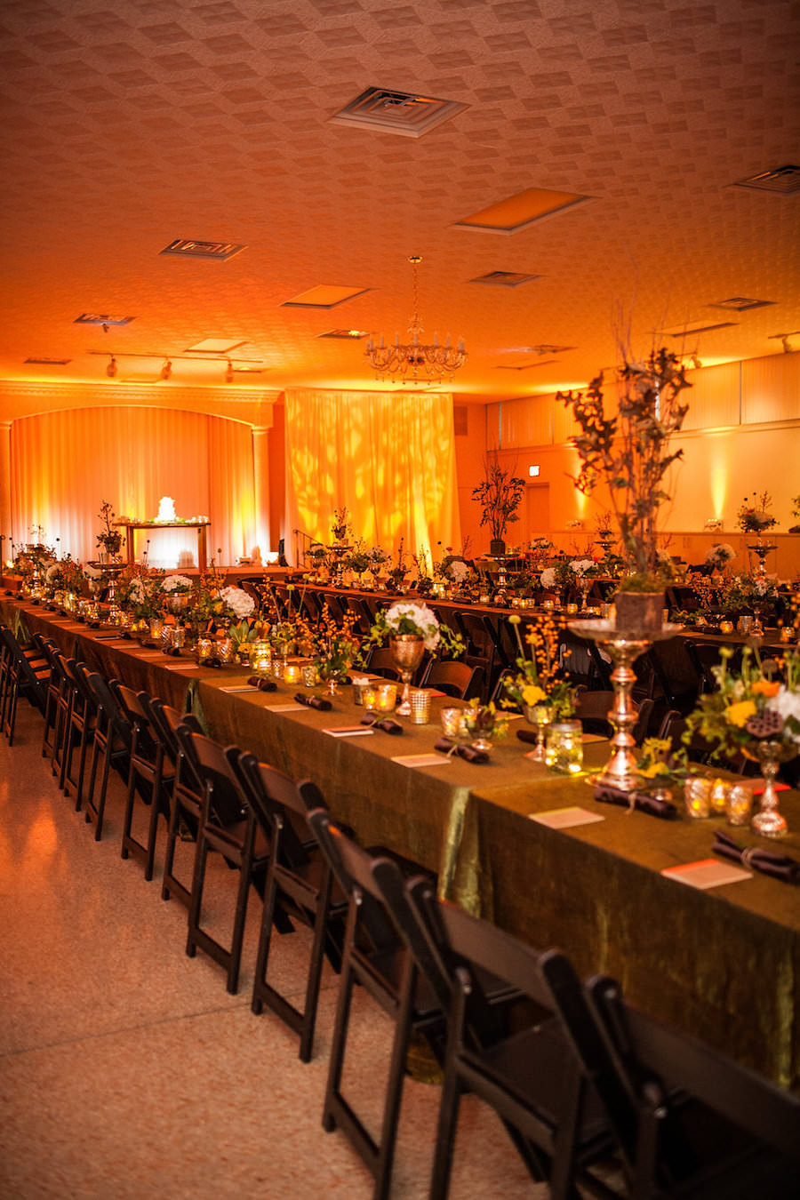Wedding Reception with Long Feasting Tables with Earth Toned Colors and Orange Uplighting | St. Petersburg Weding Venue Garden Club of St. Petersburg