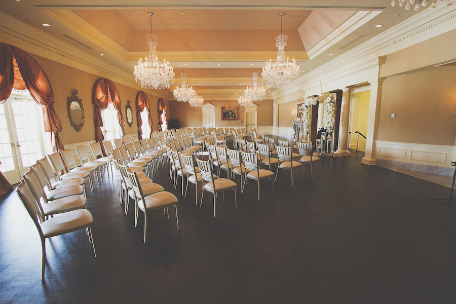 Elegant Wedding Ceremony Seating at The Oaks Club in Sarasota with Chandeliers and Romantic White Floral Decor | Sarasota Wedding Planner NK Productions