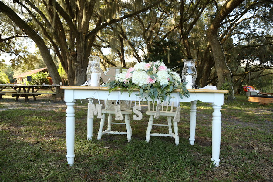 Rustic Outdoor Wedding Reception Sweetheart Table Decor with White Wooden Table with White and Pink Flowers and Initials | Lakeland Wedding Venue Rocking H Ranch
