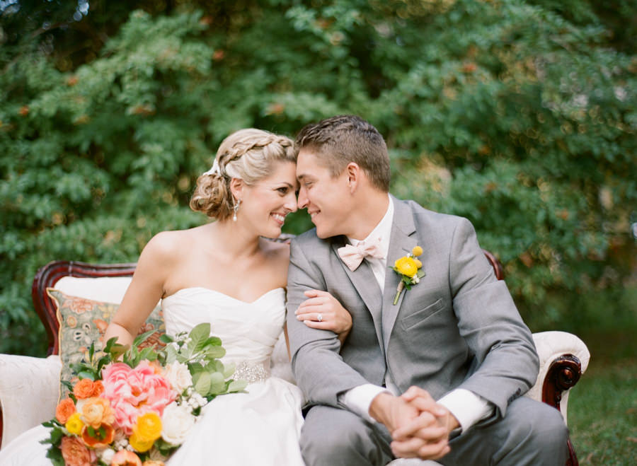 Bride with Braided Updo Hair and with Orange, Yellow and Pink Wedding Bouquet and Groom in Grey Suit | Bridal Wedding Portrait
