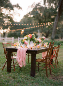 Outdoor Wedding Reception Decor with Vintage, Mis-Matched Wooden Chairs and Orange, Yellow and Pink Wedding Centerpieces with Cafe Lighting |Tampa Bay Rentals by Tufted Vintage Rentals