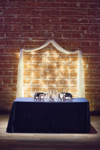 Bride and Groom Sweetheart Table with Exposed Brick Wall Backdrop at Modern, Downtown St. Pete Wedding Venue NOVA 535
