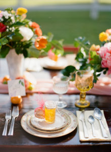 Outdoor Wedding Reception Decor with Vintage, White Vases, Citrus and Orange, Yellow and Pink Wedding Centerpieces on Wooden Farm Table with China Placesetting and Jam Favor | Tampa Bay Rentals by Tufted Vintage Rentals