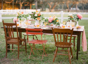 Outdoor Wedding Reception Decor with Vintage, Mis-Matched Wooden Chairs and Orange, Yellow and Pink Wedding Centerpieces with Cafe Lighting | Tampa Bay Rentals by Tufted Vintage Rentals