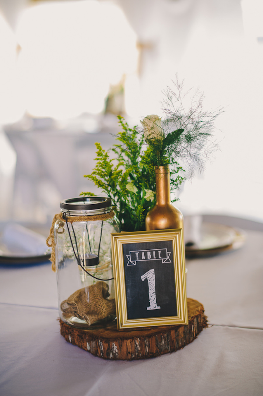 Rustic Barn Wedding Reception Table Decor with Wooden Slab Centerpieces, White Centerpieces, Painted Wine Bottles, Mason Jars, and Candles