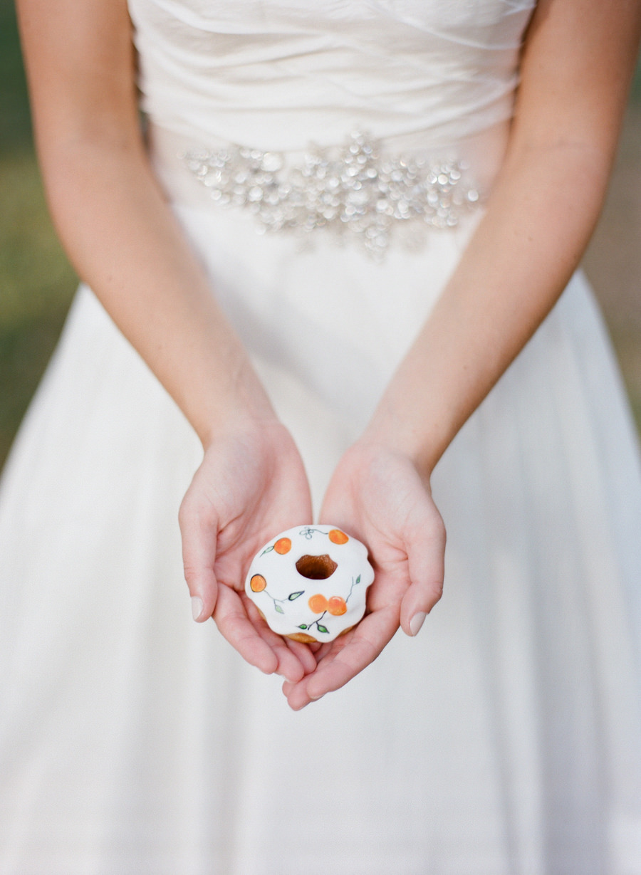Bride Holding Hand-Painted Wedding Doughnuts with Orange Citrus Decor | Wedding Cake Alternatives