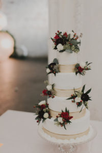 4-Tiered, White Round Wedding Cake with Gold Colored Accent and White, Red, and Plum Flowers