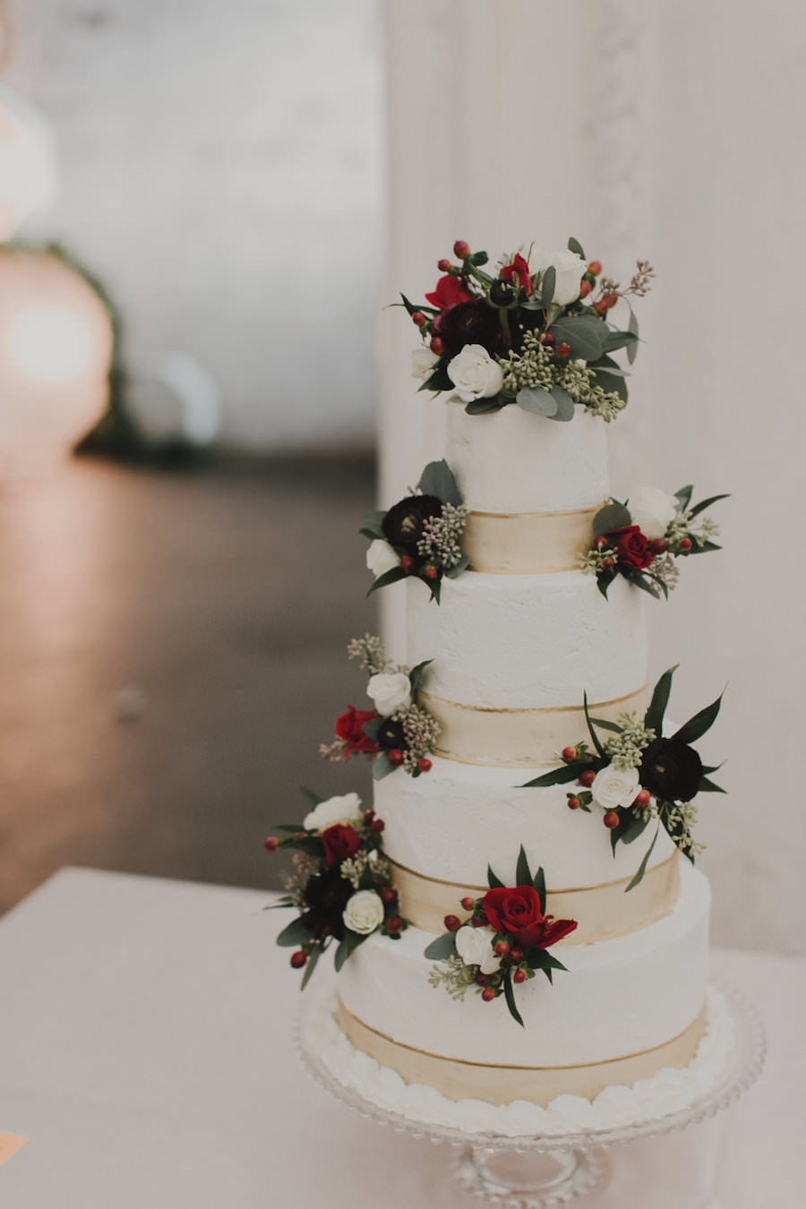 4-Tiered, White Round Wedding Cake with Gold Colored Accent and White, Red, and Plum Flowers