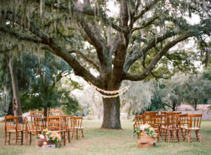 Vintage Outdoor Wedding Ceremony under Spanish Moss Tree with Mis-Matched Wooden Ceremony Chairs | Tampa Bay Rentals by Tufted Vintage Rentals