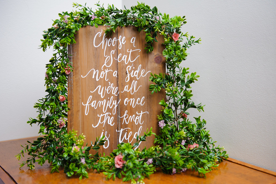 Rustic Wooden Wedding Ceremony Sign with White Calligraphy and Greenery Garland