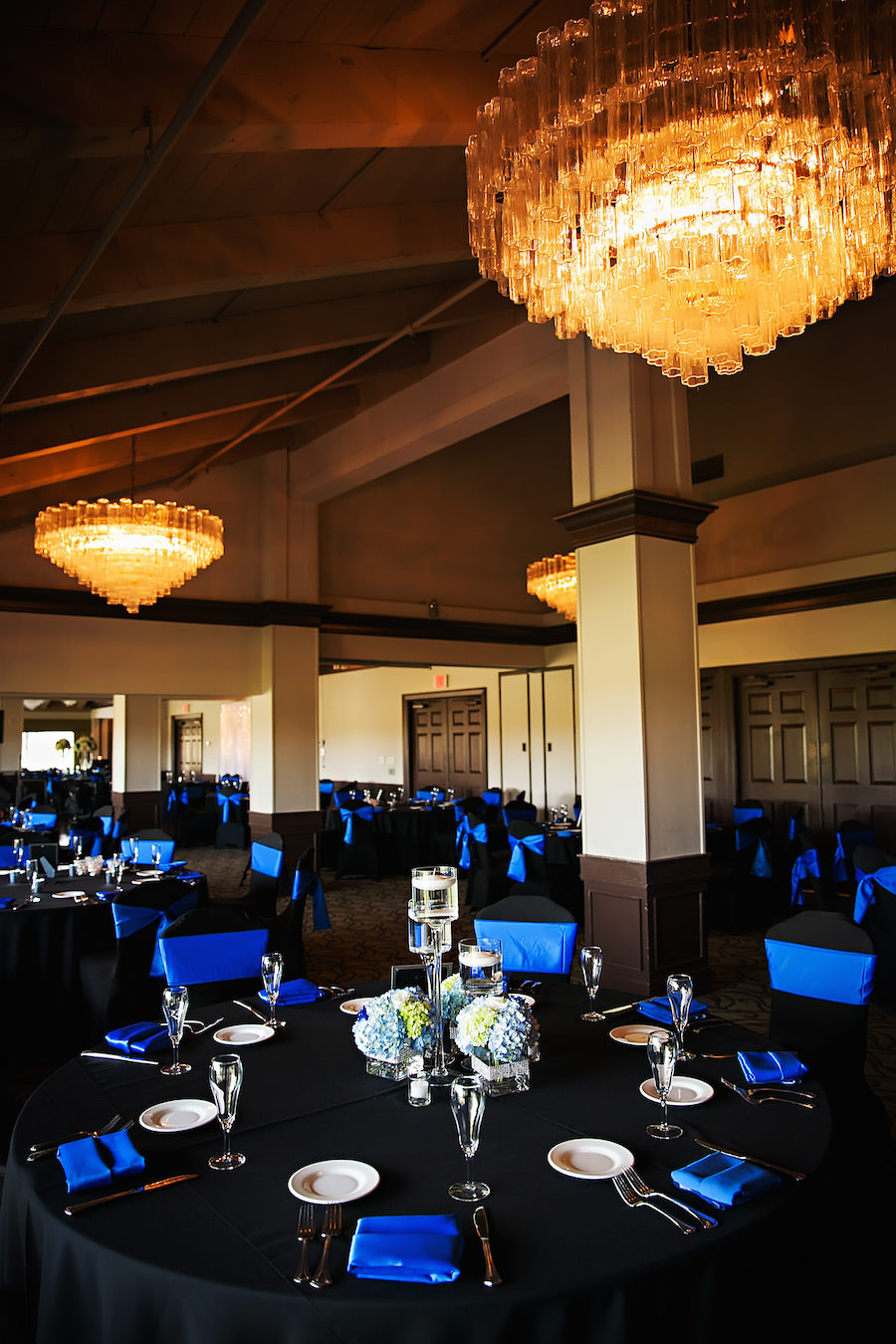 Traditional Wedding Reception Décor with Black Tablecloths, Royal Blue Chair Covers and Napkins with Blue and Ivory Hydrangea Centerpieces at Countryside Country Club Wedding Venue | Limelight Photography