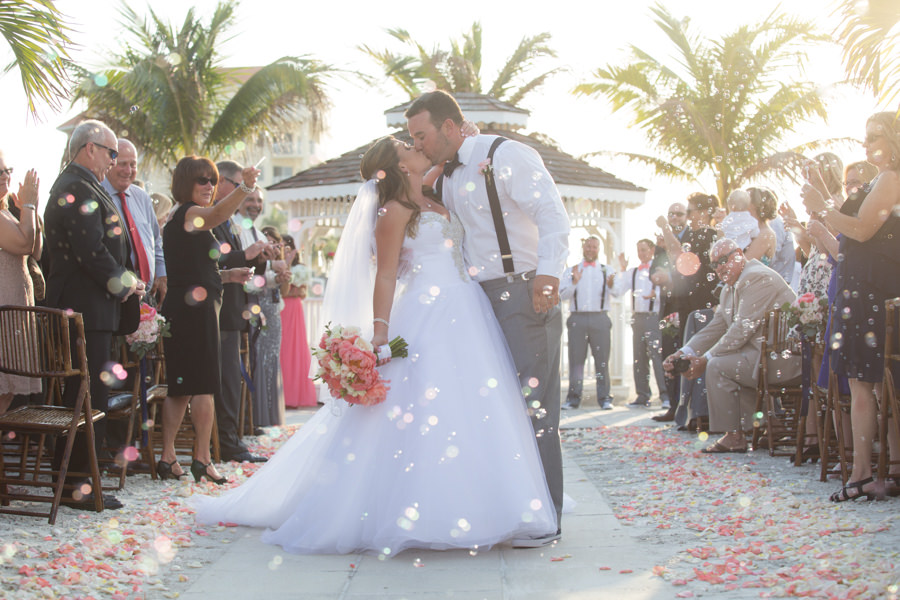 Outdoor Wedding Ceremony Bride and Groom Kiss Recessional with Bubbles Wedding Portrait | Isla Del Sol Yacht and Country Club Wedding Venue St. Petersburg FL | Coral Bridal Bouquet by Iza’s Flowers | Tulle Bridal Gown by Allure Bridal