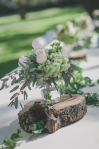 Rustic Wedding Reception Decor with Pink Roses and Greenery in Mason Jar on Wooden Slab Centerpieces
