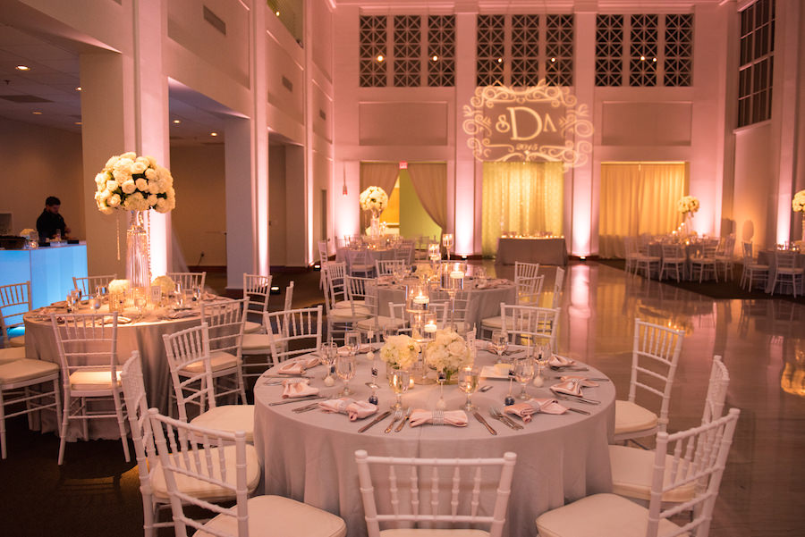 Wedding Reception all White Decor with Chiavari Chairs, Tall Floral Centerpieces and Projection Bride and Groom Initials GOBO and Pink Uplighting | Tampa Wedding Lighting Nature Coast Entertainment Services | Tampa Wedding Venue The Vault | Tampa Wedding Planner Special Moments