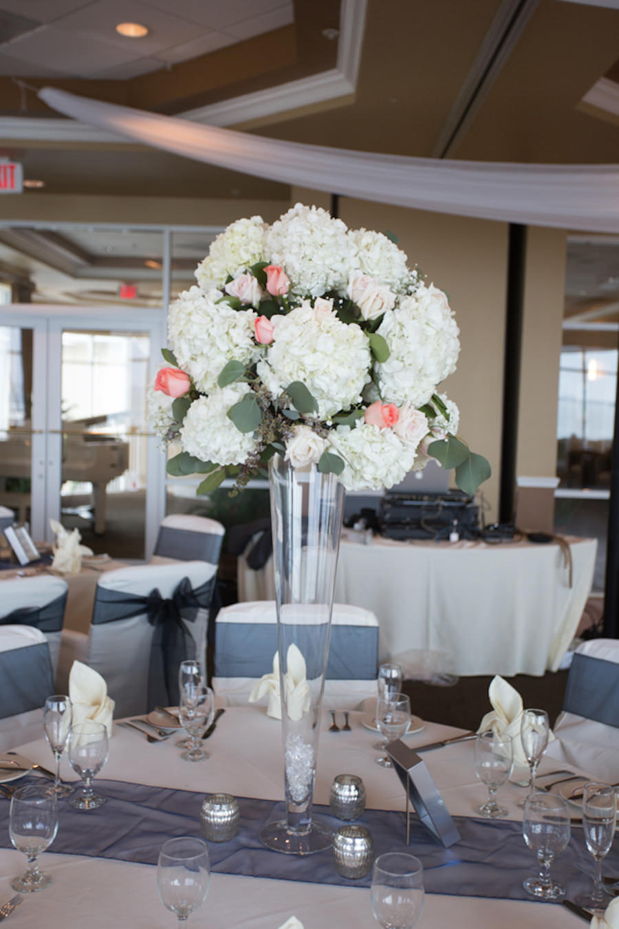 Wedding Reception Décor with Tall White and Coral Hydrangea and Rose Centerpieces on Silver Table Runners | St. Petersburg Wedding Florist Iza’s Flowers