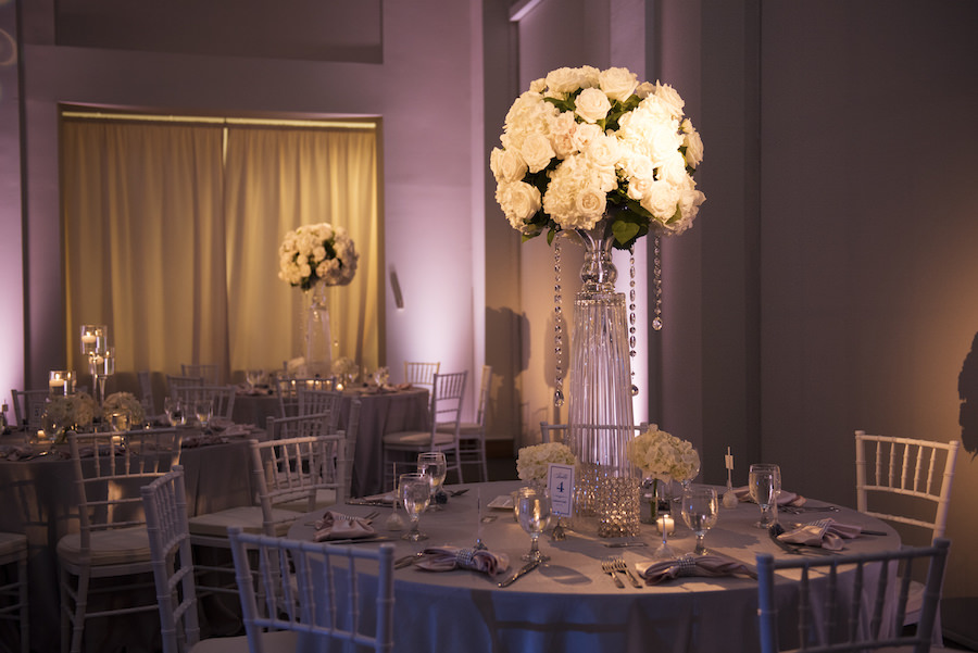 Wedding Reception Table Decor with Tall, Crystal Centerpieces with White Flowers and Crystals and White Chiavari Chairs | Pinspotting and Pink Uplighting by Tampa Wedding Lighting Nature Coast Entertainment