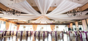 Indoor, Waterfront Tampa Wedding Reception Tabe Decor with Ceiling Drapery and Purple Bow Chair Sashes