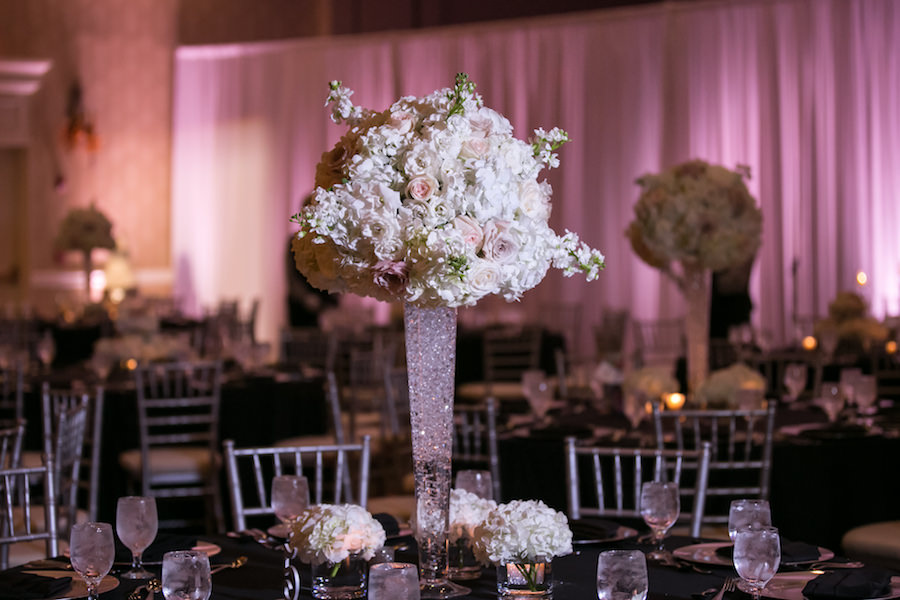 Tall, White and Blush Pink Wedding Centerpieces with Sparkle Accents and Uplighting | Black Table Linens with Silver Chiavari Chairs, Blush Pink Uplighting at Vinoy Renaissance Wedding Venue in St. Petersburg Florida | Photo by Carrie Wildes Photography