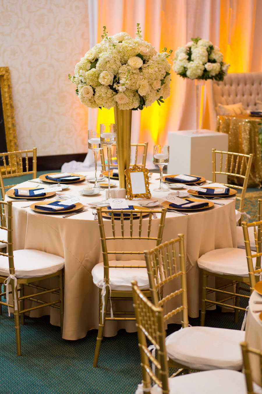 Gold Wedding Reception with Tall Ivory and White Centerpieces and Gold Chargers and Chiavari Chairs