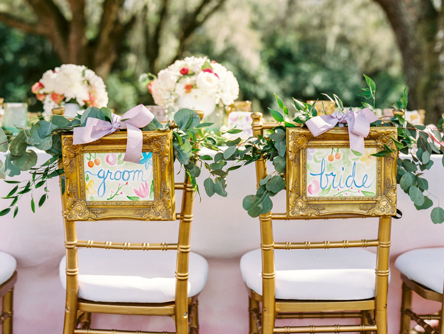 Outdoor Tampa Wedding Reception Seating with Watercolor Bride and Groom Chair Signs with Greenery with Gold Chiavari Chairs | Tampa Wedding Rental Chairs by Signature Event Rentals