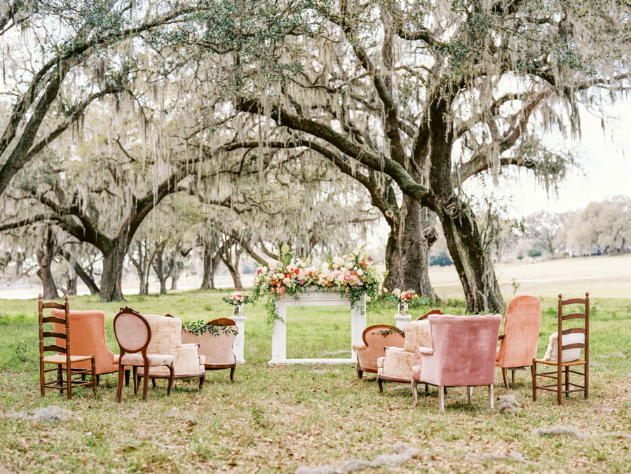 Vintage Outdoor Wedding Ceremony under Oak Trees with Mis-Matched Vintage Upholstered Chairs | Tampa Bay Vintage Wedding Rentals by Tufted Vintage Rentals