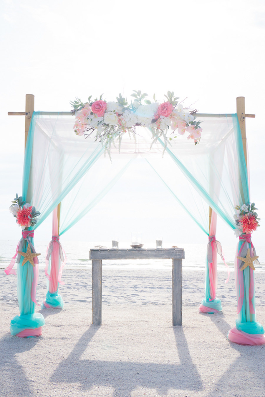 Beach, Waterfront Wedding Ceremony with Bamboo Altar and Pink and Teal Floral and Draping Accent Details | | St. Pete Beach Wedding Planners Tide the Knot Beach Weddings