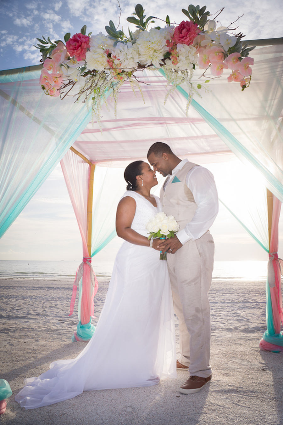 Pass-a-Grille, Waterfront Bride and Groom Beach Wedding Portrait Under Bamboo Wedding Altar with Pink and White Flowers | St. Pete Beach Wedding Planners Tide the Knot Beach Weddings