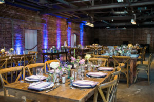 Rustic Garden Wedding Reception Table Decor with Farmhouse Table, Wooden Chairs, and Ivory and Purple Floral Centerpieces | Tampa Wedding Chair Rentals A Chair Affair | Tampa Wedding Venue CL Space