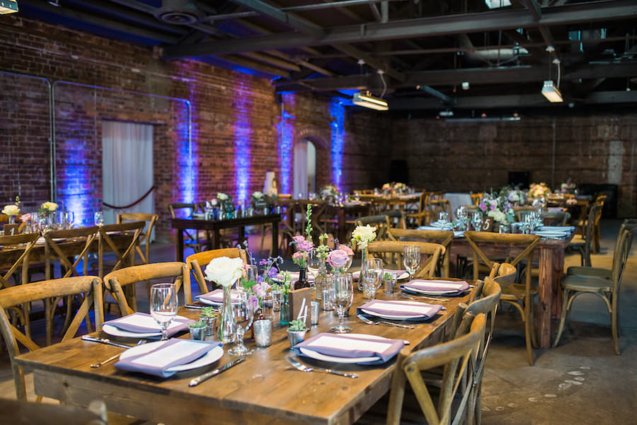 Rustic Garden Wedding Reception Table Decor with Farmhouse Table, Wooden Chairs, and Ivory and Purple Floral Centerpieces | Tampa Wedding Chair Rentals A Chair Affair | Tampa Wedding Venue CL Space