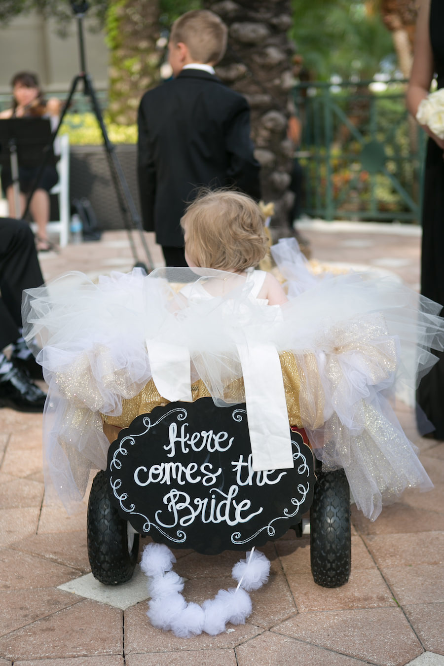 Flower Girl Walking Down The Aisle in Wagon with Chalkboard Sign | Wedding Portrait by Tampa Wedding Photographer Carrie Wildes Photography at Tampa Wedding Ceremony Venue Marriott Waterside