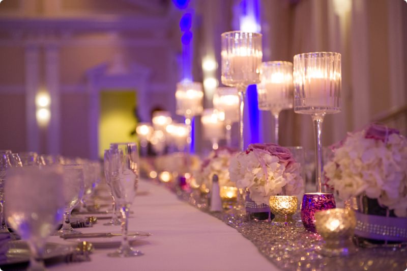 Wedding Reception Table Decor with Purple and White Floral Centerpieces and Candlelight and Sequined Table Runner