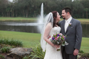 Outdoor Bride and Groom Wedding Portrait with Fountain in Ivory, Lace Wedding Dress and Purple and Pink Floral Wedding Bouquet | Tampa Wedding Venue Tampa Palms Golf & Country Club | Wedding Photographer Carrie Wildes Photography