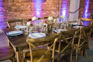 Rustic Garden Wedding Reception Table Decor with Farmhouse Table, Wooden Chairs, and Ivory and Purple Floral Centerpieces | Tampa Wedding Chair Rentals A Chair Affair | Tampa Wedding Venue CL Space