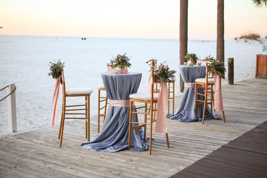 Beachfront Wedding Reception Cocktail Hour with Gold Chiavari Barstools and Purple and Pink Specialty Linens at Clearwater Beach Wedding Venue Hilton Clearwater Beach | Linens by Over The Top Rental Linens | Chairs by Signature Event Rentals | Flowers by Iza’s Flowers | Blush, Blue and Gold Wedding Ideas