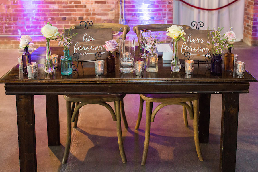 Rustic Garden Wedding Reception Sweetheart Table Decor with Farmhouse Table, Wooden Chairs, and Ivory and Purple Floral Centerpieces | Tampa Wedding Chair Rentals A Chair Affair | Tampa Wedding Venue CL Space