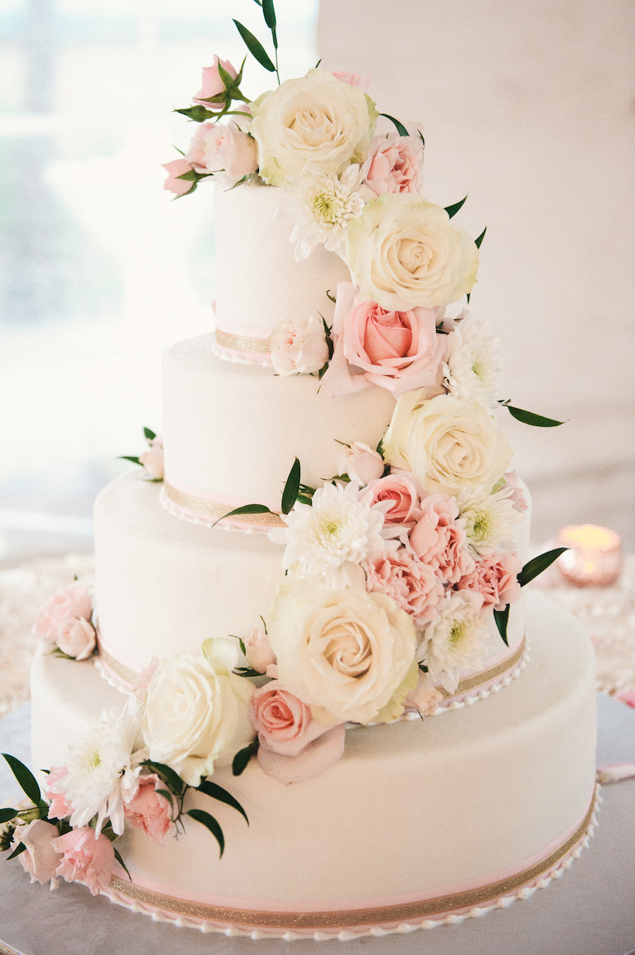 Four Tier Round White and Blush Pink Wedding Cake with Fresh Flower Roses and Pearl Decoration on Specialty Linen