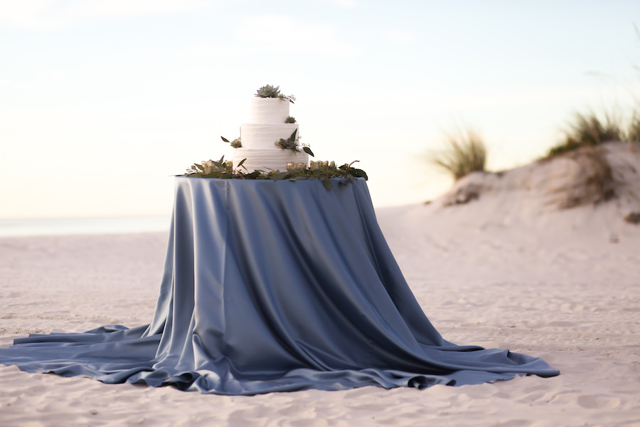 Three Tier Round White Wedding Cake on Slate Blue Satin Linen at Beach | Linens by Over The Top Linens