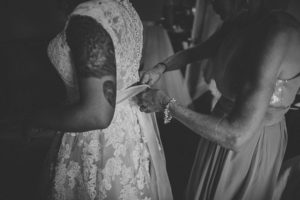 Bridesmaids Helping Put Wedding Dress on Bride