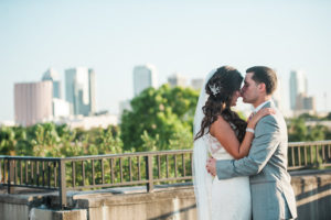 Outdoor, Bride and Groom Wedding Portrait in Lace, White Wedding Dress and Grey Groom's Suit with Downtown Tampa Skyline
